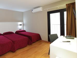 a bedroom with two beds and a desk and a window at Hotel Alameda in Benidorm