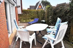 a patio with four chairs and a white table and chairs at Ferienhaus Exner hinter dem Deich in Cuxhaven