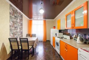 eine Küche mit einem Tisch und Stühlen sowie eine Küche mit orangefarbenen Schränken in der Unterkunft Panorama 22/2 in Krasnodar