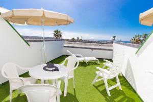 a patio with a white table and chairs and an umbrella at Vista Oasis in Maspalomas