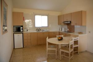 a kitchen with a table and a sink and a refrigerator at Club Aphrodite in Erimi