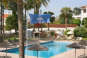 a flag flies next to a swimming pool with umbrellas at Club Aphrodite in Erimi
