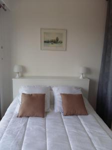a white bed with two brown pillows on it at Maxime plage in Sainte-Maxime