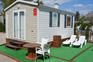 a tiny house with white chairs and a table at Camping Valencia el Saler in El Saler