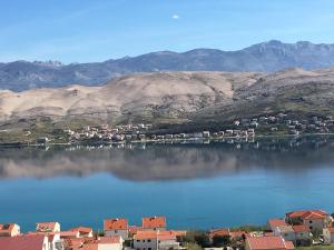 a large body of water with houses and mountains at House with a garden 50m from the sea in Pag