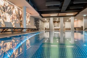 a swimming pool with chairs and a tile wall at Chalet Obergurgl Luxury Apartments in Obergurgl