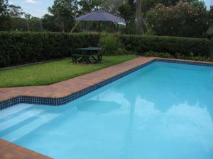 a swimming pool with a table and an umbrella at The Wayfarer Motel in Muswellbrook