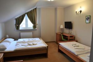 a bedroom with two beds and a window and a tv at Hotel Trzy Podkowy*** in Biskupiec