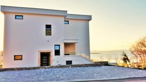 a large white building with a sunset in the background at Apartment Villa Vala in Malinska