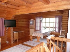 a living room with a television in a log cabin at Vuorenhelmi in Rutalahti