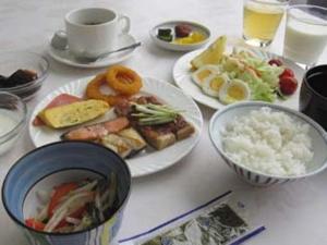 Smile Hotel Towada في تووادا: طاولة بيضاء مليئة بأطباق الطعام والمشروبات