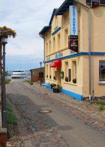 ein Gebäude auf einer Straße mit einem Boot im Hintergrund in der Unterkunft Hotel-Pension Zur Mole in Wiek auf Rügen 