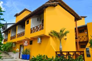 a yellow building with a palm tree in front of it at Pousada Pérola Do Morro in Morro de São Paulo