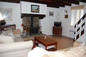 een woonkamer met een bank en een open haard bij Coet Moru Gites - Rose Cottage in Crédin