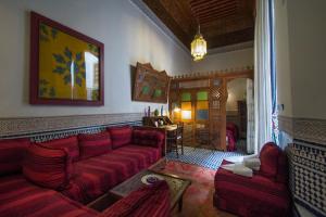 a living room with a red couch and two chairs at Riad Dar Cordoba in Fès