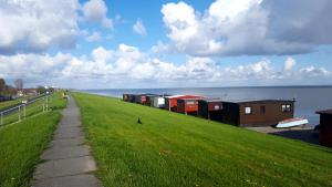 a grassy hill with houses on it next to the water at Hotel Seerose in Wilhelmshaven +18 photos