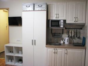 a kitchen with white cabinets and a sink and a microwave at Bohemian Dawn Apartment in Belgrade