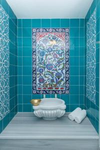a blue tiled bathroom with a bath tub and a rug at Darussaade Istanbul Hotel in Istanbul