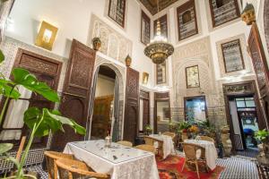 una sala da pranzo con tavoli, sedie e lampadario a braccio di Riad Dar Cordoba a Fes