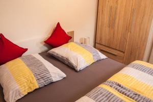 ヴァンガーオーゲにあるStrandperle Wangeroogeのベッドルーム1室(ベッド2台、赤と黄色の枕付)