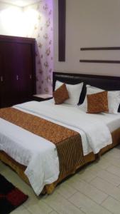 um quarto com 2 camas com lençóis brancos e almofadas em Lamset Aseer Chalets em Khamis Mushayt