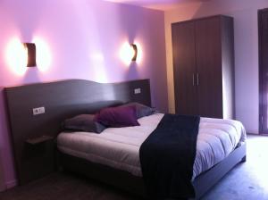 1 Schlafzimmer mit einem Bett mit lila Wänden und 2 Leuchten in der Unterkunft The Originals City, Hôtel des Arts, Montauban (Inter-Hotel) in Nègrepelisse