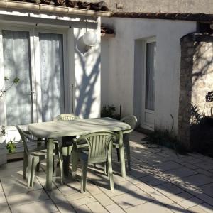 サント・マリー・ド・レにあるMaison de 2 chambres avec terrasse amenagee et wifi a Sainte Marie de Re a 1 km de la plageの木製テーブルと椅子付きのパティオ