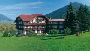 una casa grande en un campo verde con montañas en el fondo en Bruckerhof, en Puchberg am Schneeberg