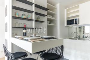 a kitchen with a bar with chairs and wine glasses at Résidence Palais Étoile in Paris