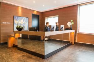 two women standing at a reception desk in a hotel lobby at Adagio Paris 19ème Cité de la Musique in Paris