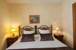 エステポナにあるApartamentos Turísticos Casa de La Borregaのベッドルーム1室(ベッド1台、ナイトスタンド2台、ランプ2つ付)