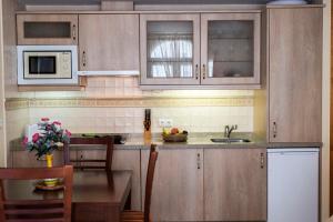 una cucina con armadi in legno, lavandino e tavolo di Apartamentos Turísticos Casa de La Borrega a Estepona