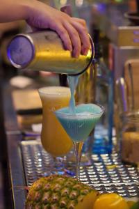 ハンメルブルクにあるHotel Deutsches Hausの青い飲み物をマティーニグラスに注ぐ者