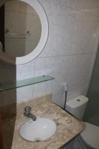 y baño con lavabo, espejo y aseo. en Pousada Flor Dália, en Natal