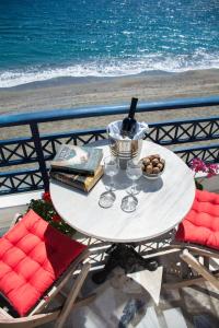 a white table with books and wine glasses on a beach at Paradise Studios in Myrtos