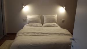un letto con lenzuola e cuscini bianchi in una stanza di Alona a Kefar Weradim