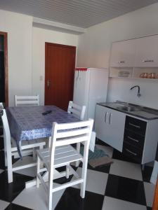 cocina con mesa, sillas y nevera en Pousada Pingo de Ouro, en Florianópolis