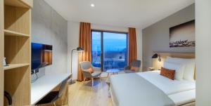 Ydalir Hotel في ستافانغر: غرفة فندقية بسرير ونافذة كبيرة
