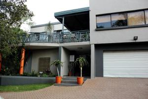 a white house with a balcony and a garage at Koru Guesthouse in Pretoria