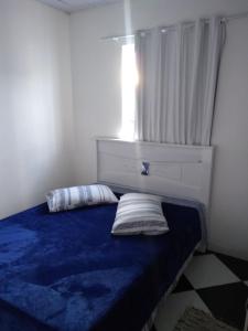 1 dormitorio con cama azul y ventana en Pousada Pingo de Ouro, en Florianópolis