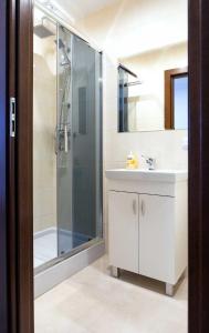 een badkamer met een witte wastafel en een douche bij M&A GUEST ROOMS in Łomża