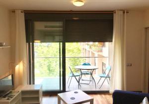 ビラノバ・イ・ラ・ジャルトルにあるAmeba cozy apartment by HLCLUB Agencyのリビングルーム(ガラスのスライドドア、テーブル、バルコニー付)
