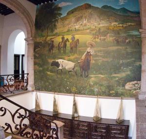 a mural on the wall of a building with horses and cows at Hotel Herencia By Hosting House in Morelia