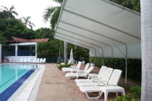 a row of white lounge chairs next to a swimming pool at girardot resort apto102 in Ricaurte