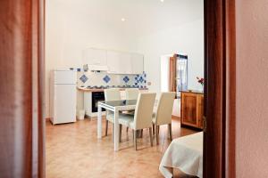 a kitchen with a table, chairs and a refrigerator at Ada's Guest house in Bosa