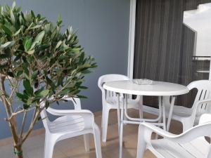 ein weißer Tisch, weiße Stühle und ein Baum in der Unterkunft Vasilas Holiday Apartment #1 in Larnaka