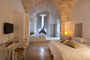 a bedroom with a bed and a bathroom with a tub at Hotel Corte Altavilla in Conversano
