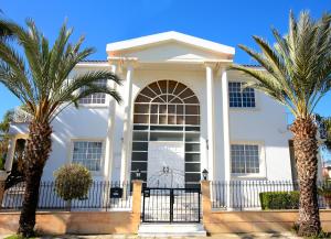 een wit huis met palmbomen ervoor bij The White House in Larnaka