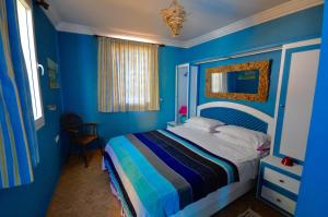 a bedroom with blue walls and a bed with a striped bedspread at Sallys in Mirleft