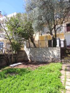 a stone fence and trees in front of a house at Guest House Jelena in Budva